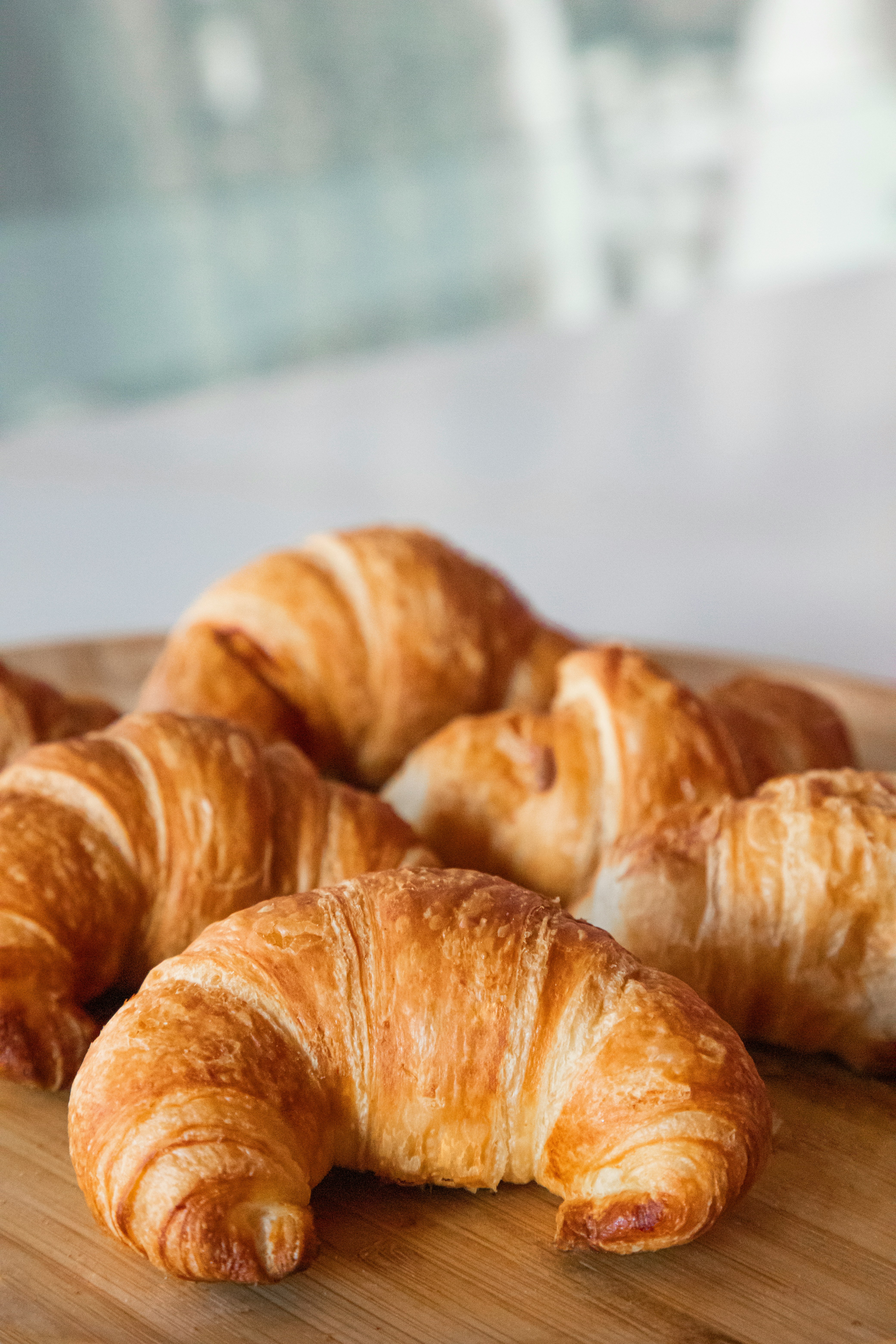 Several croissants on a wooden board.