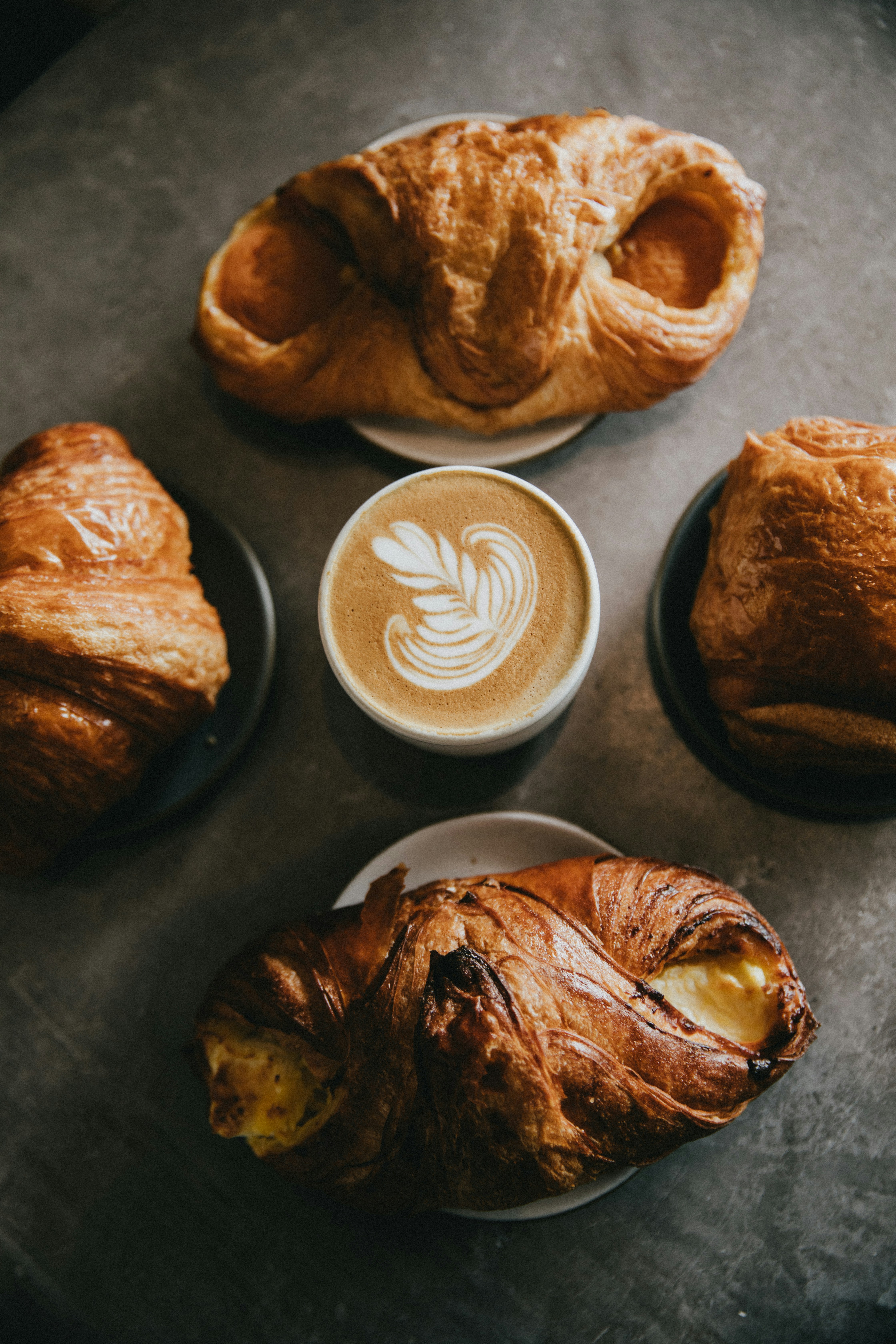 Four pastries surrounding a cup of coffee.